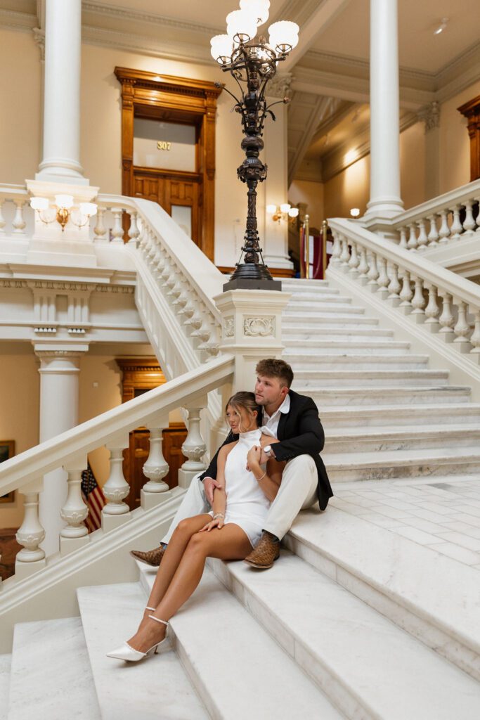 couple sitting together on the steps inside the Georgia state capitol building during an engagement session