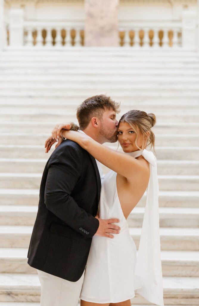 couple standing together at the steps of the capitol building in Georgia while wearing a suit and white dress