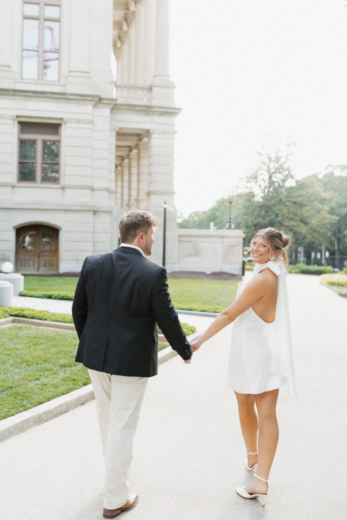 soon to be bride and groom holding hands and walking outside of the Georgia State building