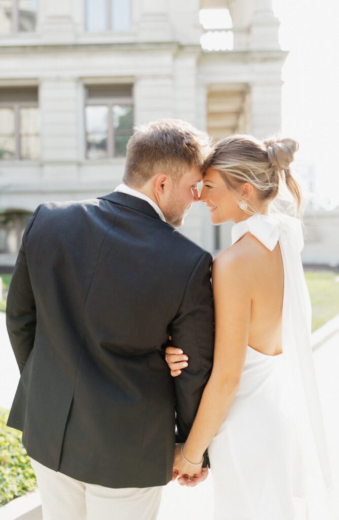 couple leaning their forehead on each other while holding hands and walking outside the state capitol building