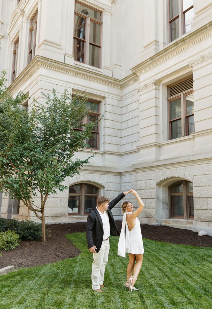 soon to be bride and groom standing with each other happily on the green grass of the capitol building