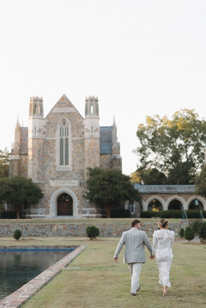 engaged couple walking across the greens along the water on the grounds of berry college