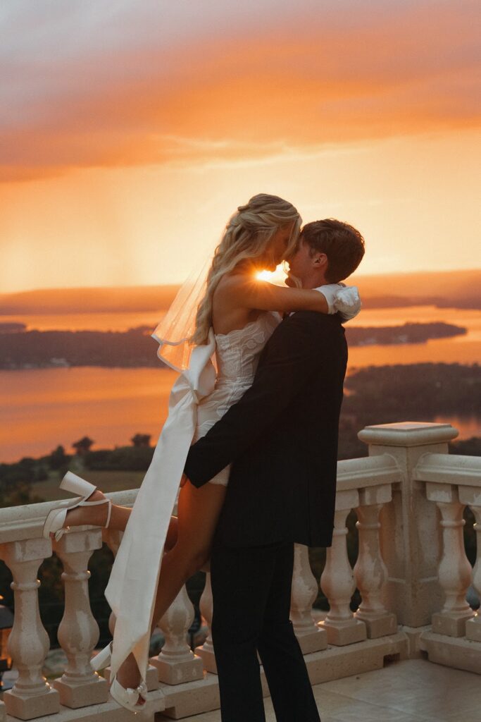 groom holding bride and kissing romantically in the sunset at their southern style luxury wedding