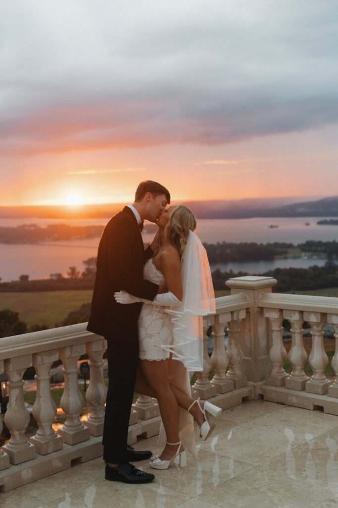 Groom leaning down and kissing bride at a European style wedding venue during the sunset 