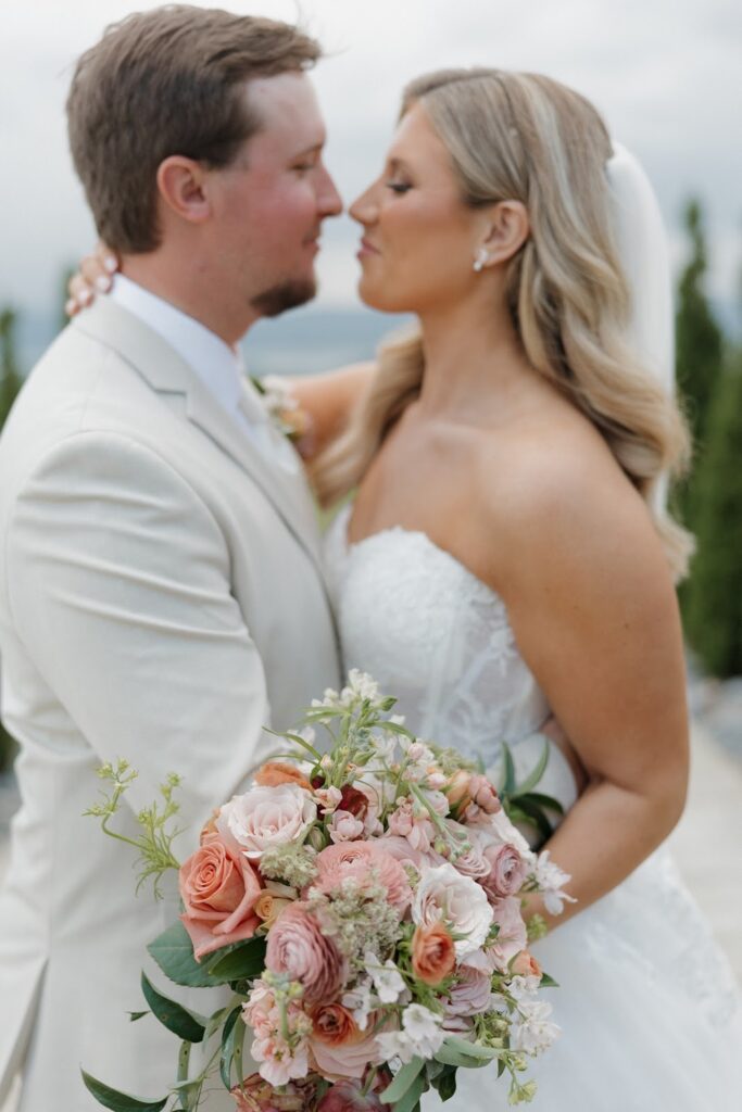 springtime bride and groom kissing in front of the mountains at stone haven weddings