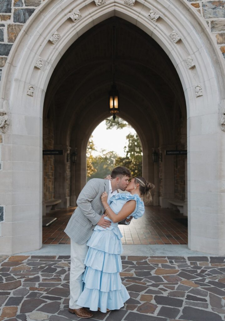 man dipping his fiance in front of historic walkway