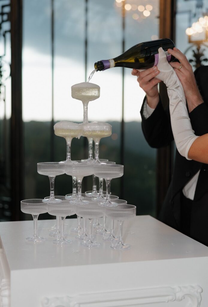 Bride and Groom pouring champagne down a tower of glasses at stone haven weddings